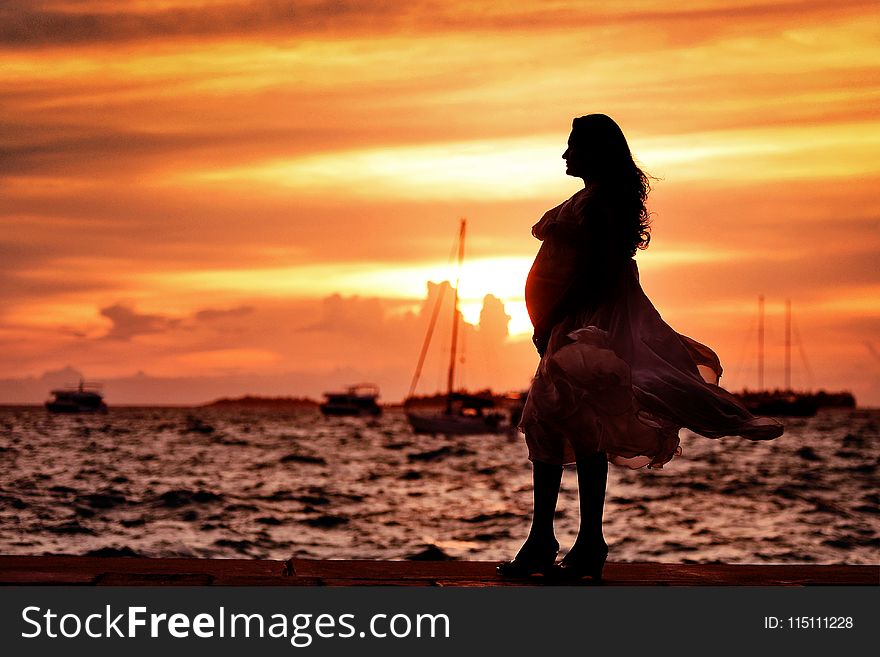 Pregnant Woman Standing Near Seashore during Sunset