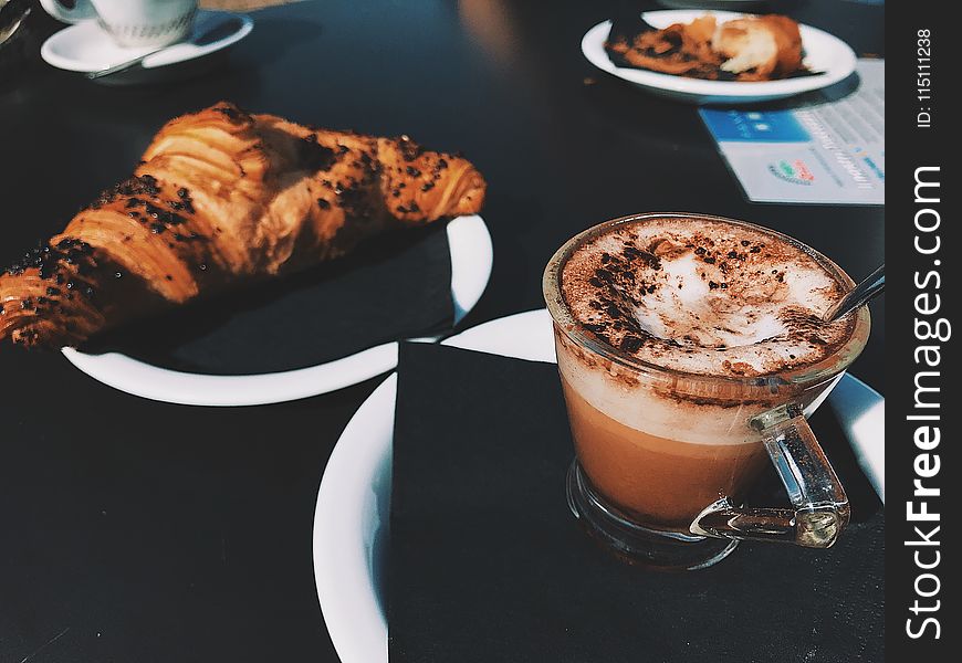 Clear Glass Cup Filled With Cappuccino Beside Croissant Bread