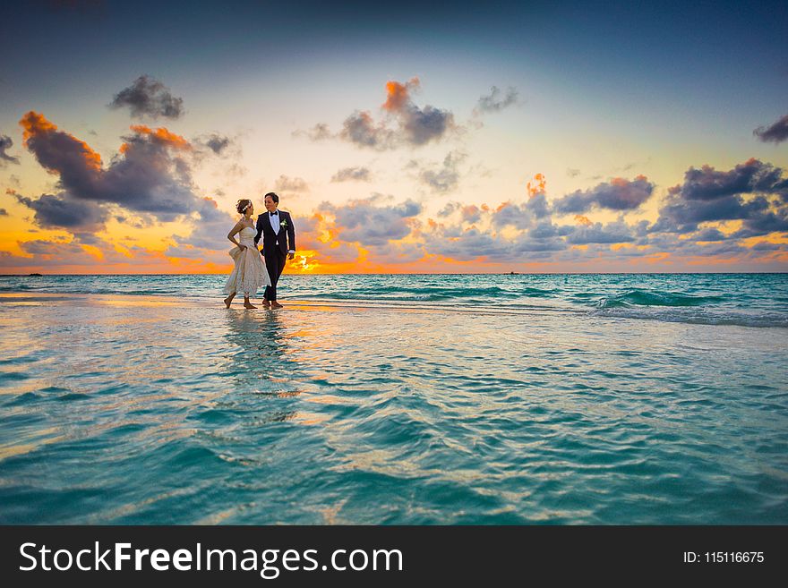 Man and Woman Walking of Body of Water