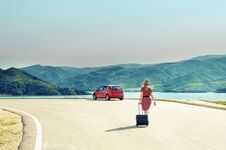 Woman With Suitcase At The Road With A Red Car Royalty Free Stock Image