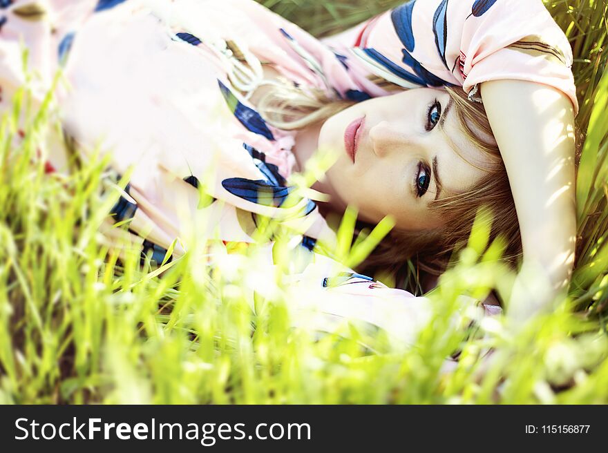 Young woman enjoying the lying on her back on the green grass in the garden.