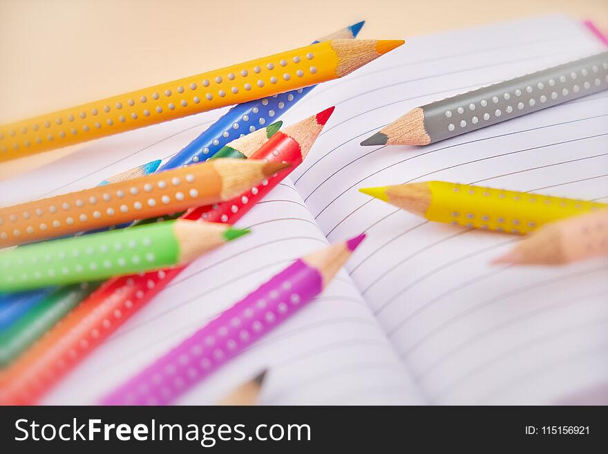 Open notebook and colorful pencils on table.