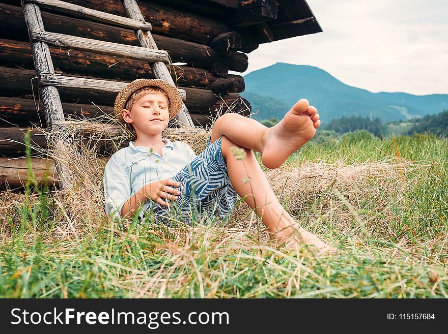 Boy In Straw Hat Lies In Hay Near The Barn