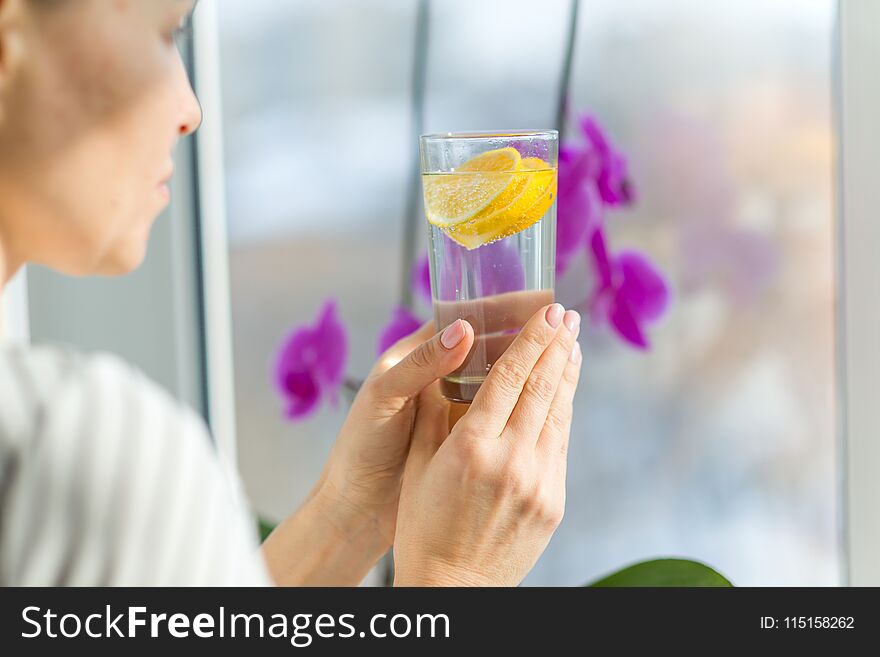 Woman drinking summer refreshing fruit flavored infused water with fresh organic lemon. Healthy eating, diet concept. Woman drinking summer refreshing fruit flavored infused water with fresh organic lemon. Healthy eating, diet concept.