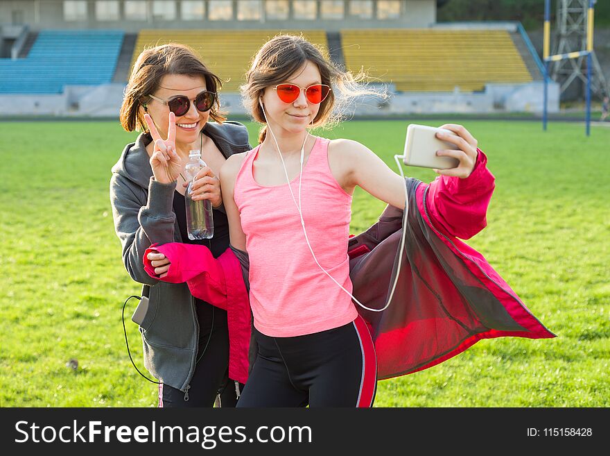 Mother and daughter teenager resting after workout at stadium. Photographed together selfi photo. Mother and daughter teenager resting after workout at stadium. Photographed together selfi photo.