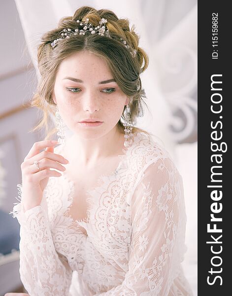 Portrait of beautiful bride. Morning of the bride. Wedding morning. Makeup. Bride with cones and fair hair. Fragile bride in white lace negligee