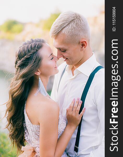 Elegant curly bride and groom outdoors on the background the lake. Groom and Bride. wedding dress. Bridal wedding bouquet of flowers