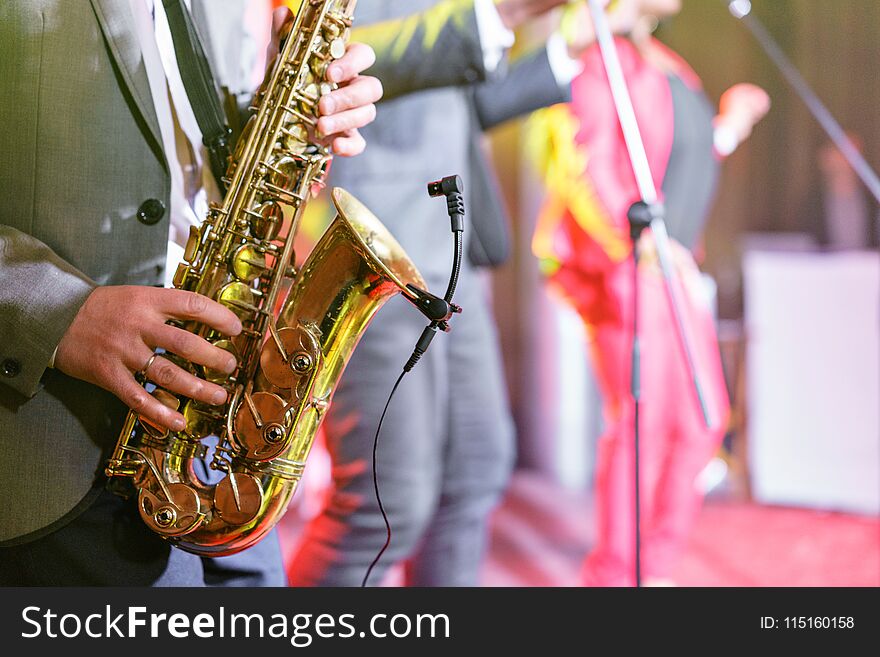 A young man in a suit playing on saxophone. Elegant saxophonist plays jazz. close-up musical instrument, sax in the