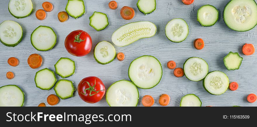 Wide photo vegetables on wooden background. Top view of cucumbers, tomatoes, zucchini, carrots.
