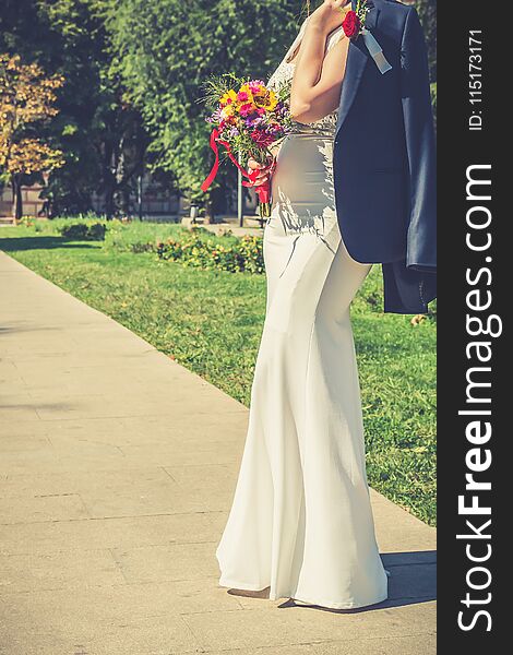 Elegant Bride Holding Groom`s Jacket Over Her Shoulder