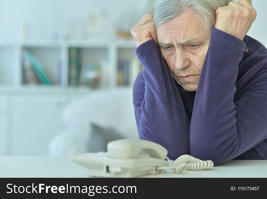 Portrait of upset senior woman with phone