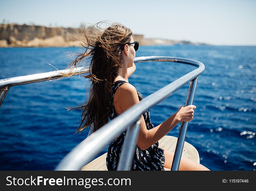 Young woman in sunglasses relax on yacht in sea. Beautiful seascape
