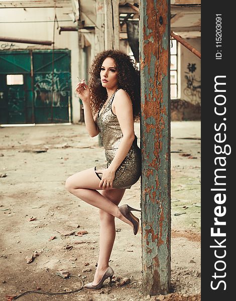 Photo of Woman Smoking Cigarette While Leaning on Wooden Post