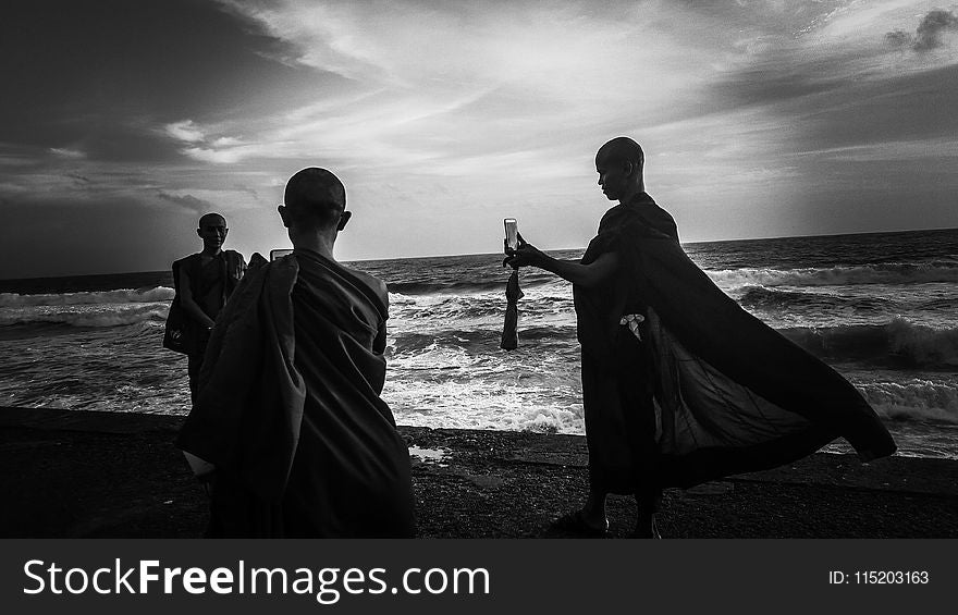 Greyscale Photography of Three Monks Near Ocean