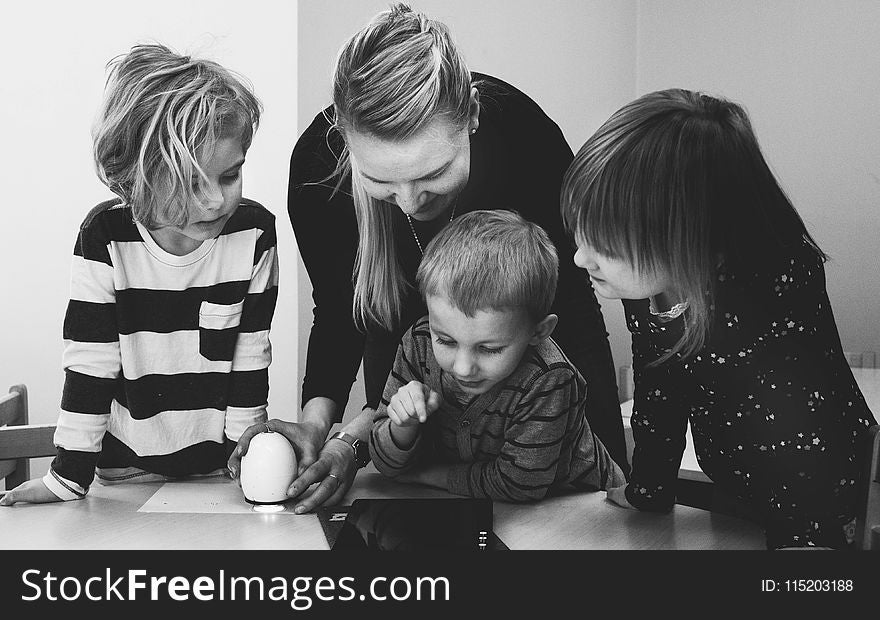 Grayscale Photo of Mother and Three Children Playing