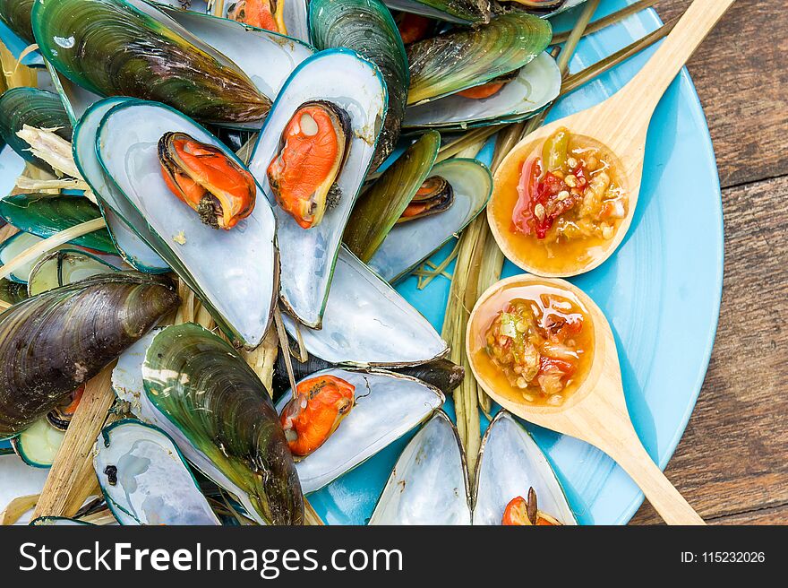 Steaming mussel With delicious sauce on dish with wood table seafood style.