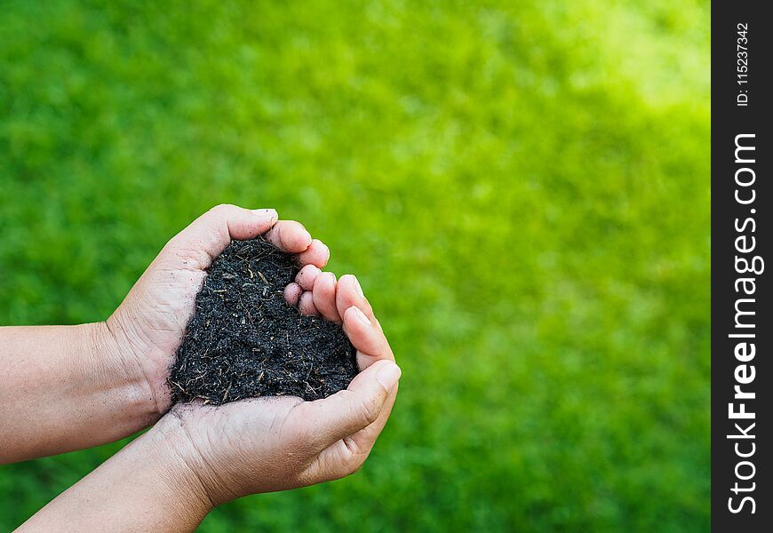 Earth day, save the earth, love concept. the woman hand holding a soil on green grass blur background.