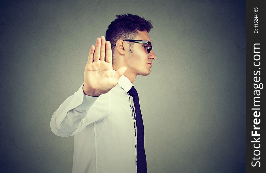 Annoyed angry man with bad attitude giving talk to hand gesture isolated on gray background. Negative human emotion face expression feeling body language