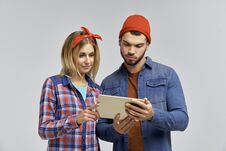 Young Couple With Attractive Looks In Casual Hipster Clothes Look Attentively At The Tablet And Learn Something. Stock Photo Young Couple With Attractive Looks In Casual Hipster Clothes Look Attentively At The Tablet And Learn Something. Stock Photo