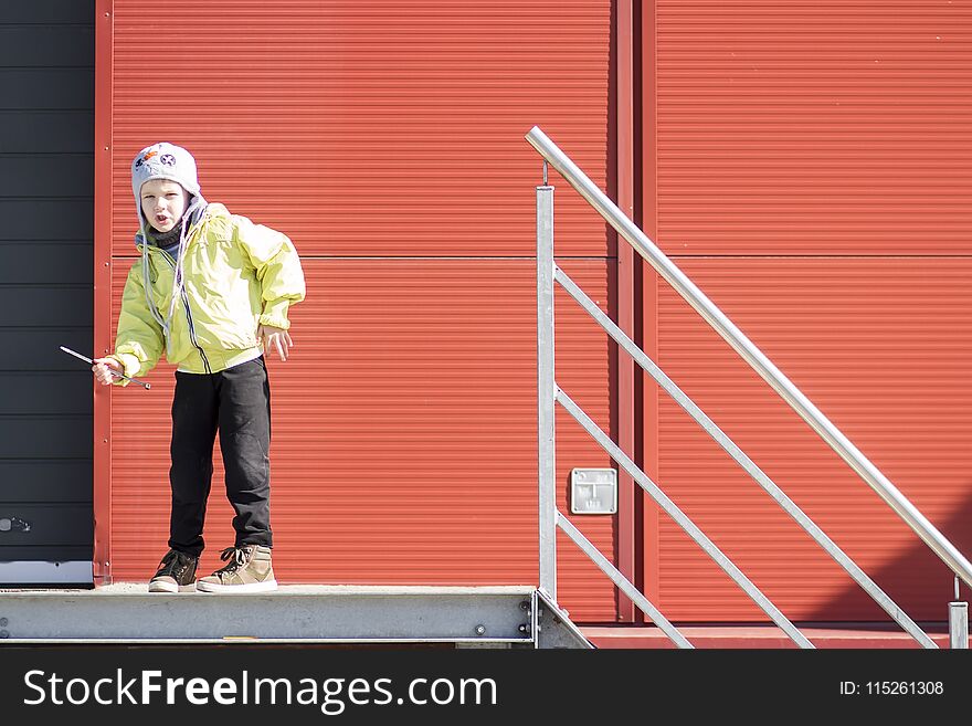 Boy moves like robot. boy plays in territory of industrial plant against background of metal profile wall. Portrait of boy