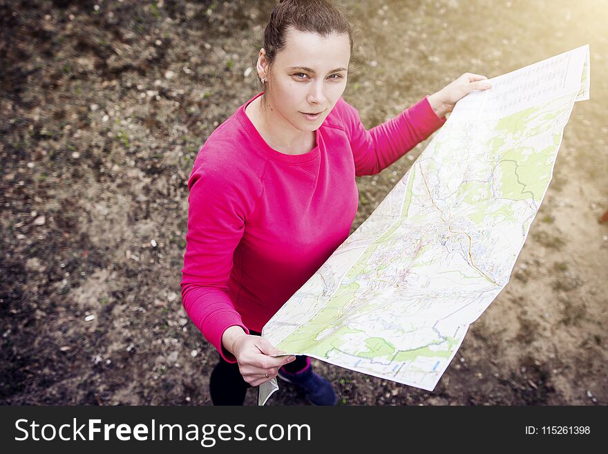 Girl with map in her hands on hike. Athlete orienteering in wild. girl is traveling with card in nature. Woman on active rest.
