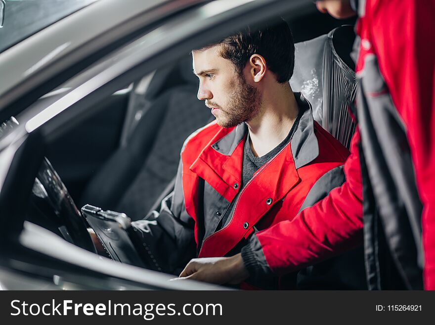 Professional car mechanic working in auto repair service with special laptop for automatic fix. Professional car mechanic working in auto repair service with special laptop for automatic fix