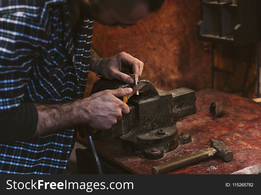 Man works in carpentry workshop. He cuts knife with wooden wedge. Different tools are on workbench. Men at work. Hand work. Man works in carpentry workshop. He cuts knife with wooden wedge. Different tools are on workbench. Men at work. Hand work.