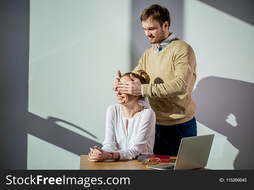 Handsome businessman surprising his colleague, cover her eyes