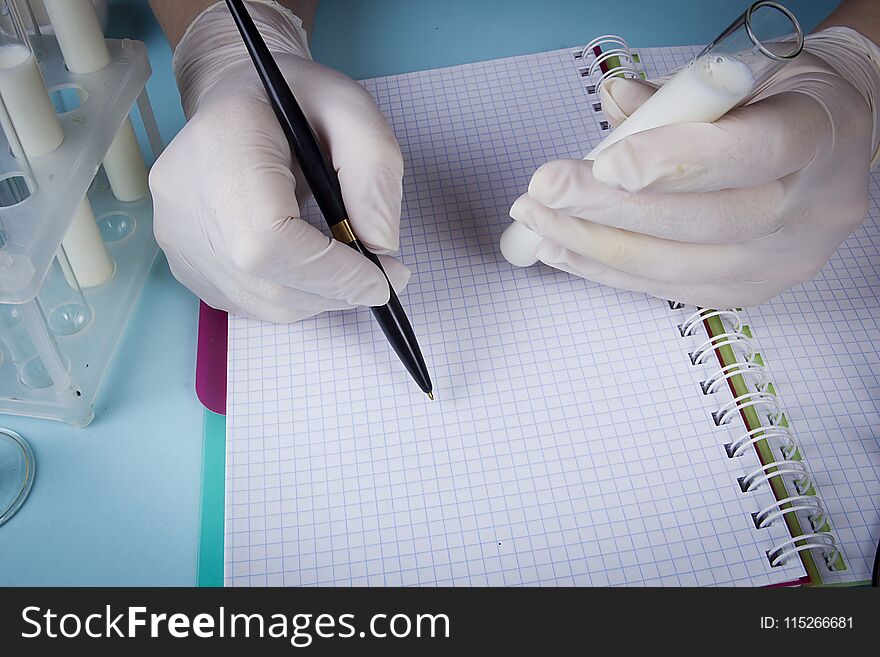 Hands in latex gloves with test tubes record in a notebook