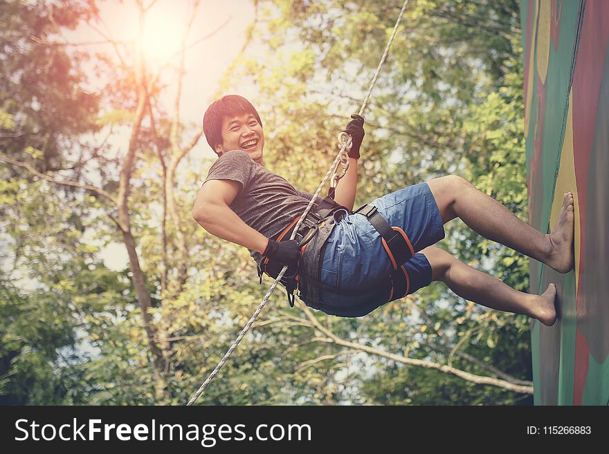 asian younger man hanging on clip hiking safety rope and laughing with happiness emotion