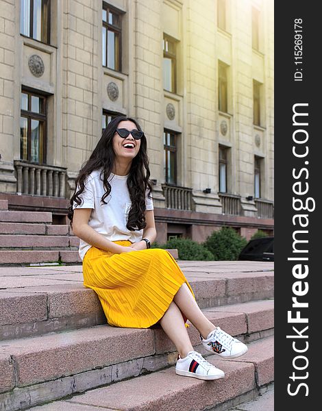 Woman Wearing White Shirt and Yellow Skirt Sitting on Brown Concrete Brick Stairs