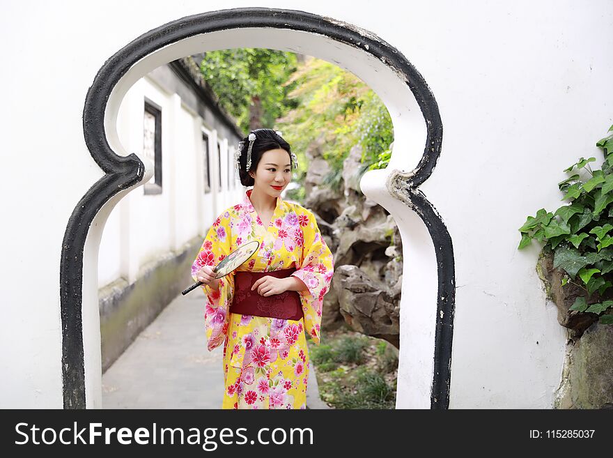 Traditional Asian Japanese beautiful woman wears kimono in a spring garden park stand by bamboo enjoy free time fan
