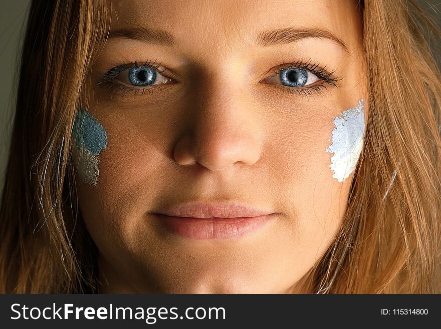 Portrait of a woman with the flag of the Argentina painted on her face. Young female caucasian model closeup. Football, soccer, fan concept. Human emotions, facial expressions concepts