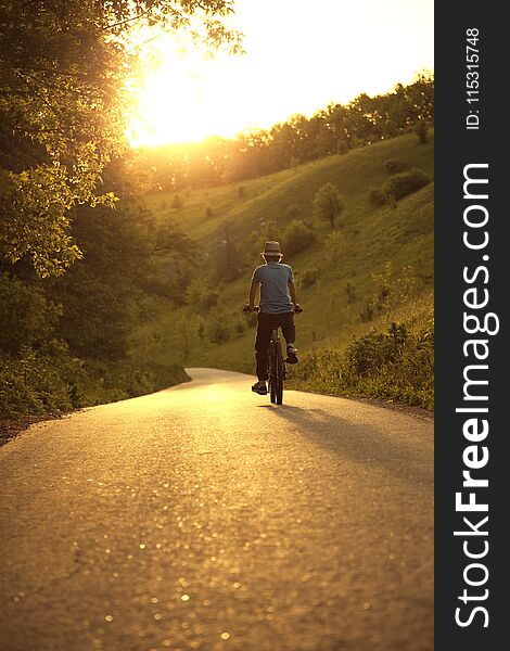 Teenager Riding A Bicycle On The Road Summer Sunlit