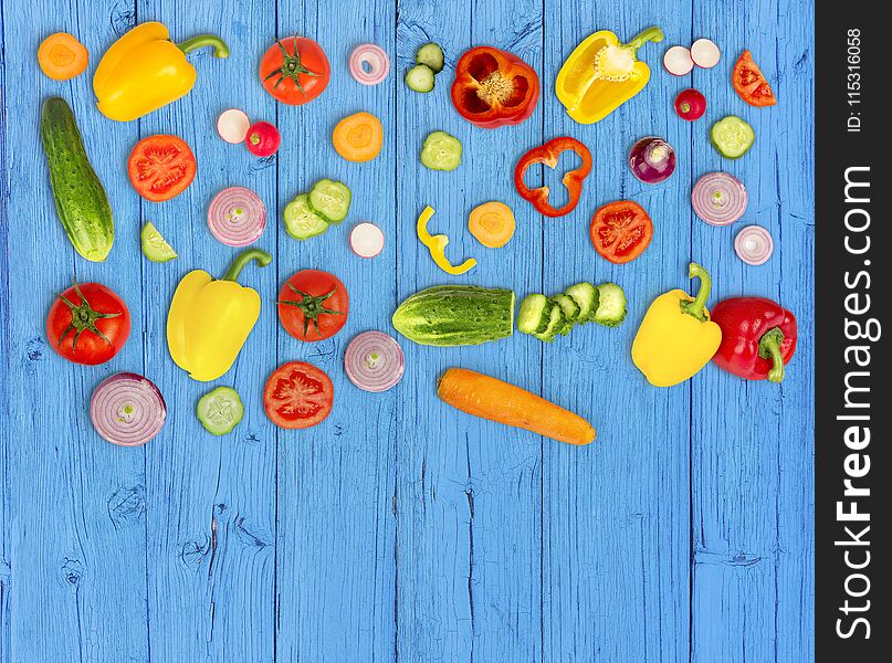 Vegetable Mix On Blue Wooden Ibackground. Fresh Yellow Pepper, Chopped Tomatoes, Onion, Round Cucumber Slice, Carrot, Radish.