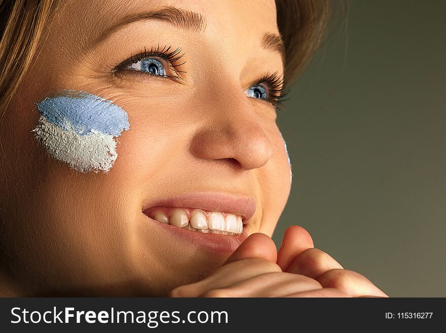 Portrait of a woman with the flag of the Argentina painted on her face. Young female caucasian model closeup. Football, soccer, fan concept. Human emotions, facial expressions concepts