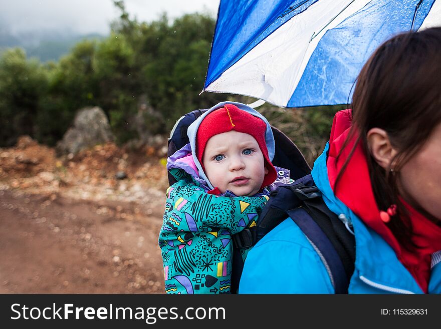 A woman carries a child in a backpack.