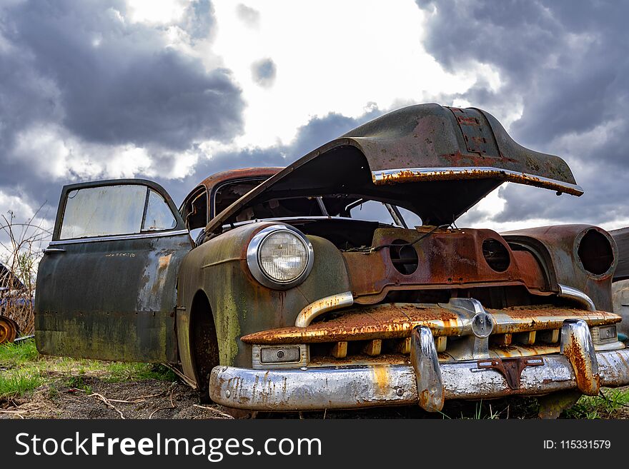 Old car waiting for a rebuild. Low angle view of an old car against a dramatic sky with room for copy. Old car waiting for a rebuild. Low angle view of an old car against a dramatic sky with room for copy