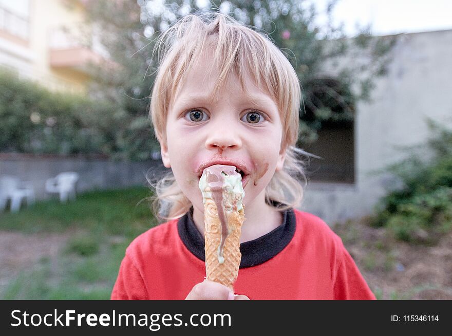 Cute boy eating ice-cream during walk in tropical resort