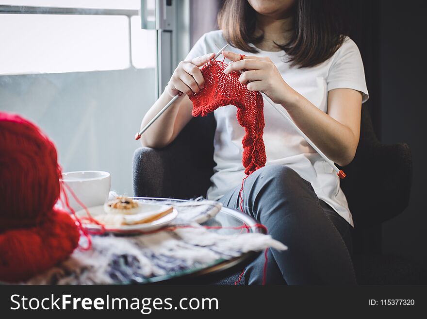 Close Up Shot Of Young Woman Hands Knitting A Red Scarf Handicraft In The Living Room On Terrace At Home