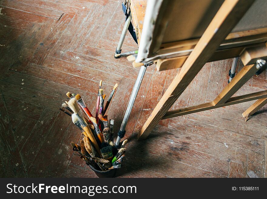 Brushes for drawing on an old wooden easel, stand on the floor