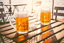 Two Glasses Of Light Beer With Foam On A Wooden Table.On A Boat. Garden Party. Natural Background. Alcohol. Draft Beer. Landscape, Stock Photography Two Glasses Of Light Beer With Foam On A Wooden Table.On A Boat. Garden Party. Natural Background. Alcohol. Draft Beer. Landscape, Stock Photography