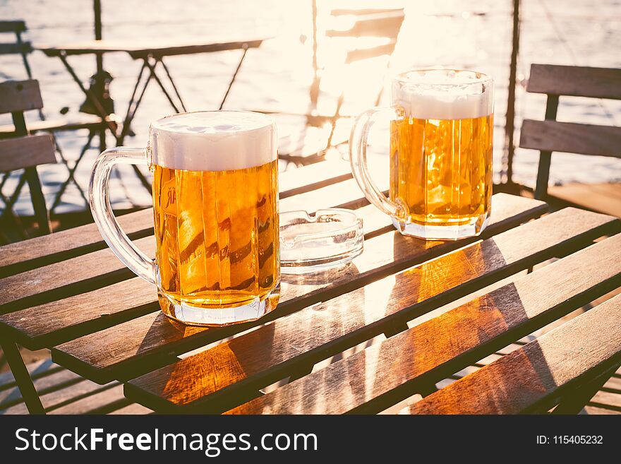 Two glasses of light beer with foam on a wooden table.On a boat. Garden party. Natural background. Alcohol. Draft beer. Landscape