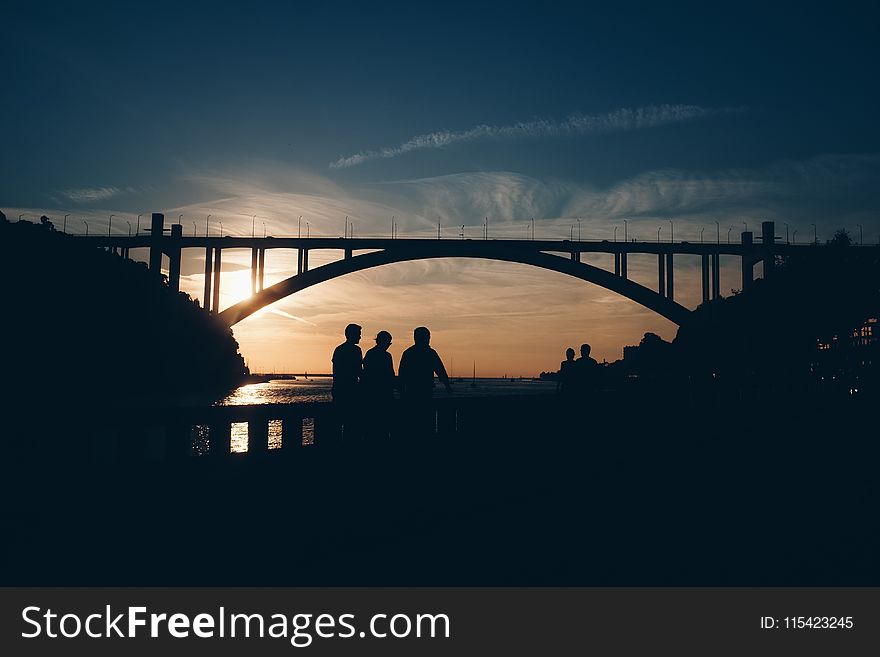 Silhouette of People Standing Near the Bridge