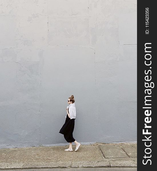 Woman Wearing Black Maxi Dress and Pair of White Flats Standing Beside Gray Wall