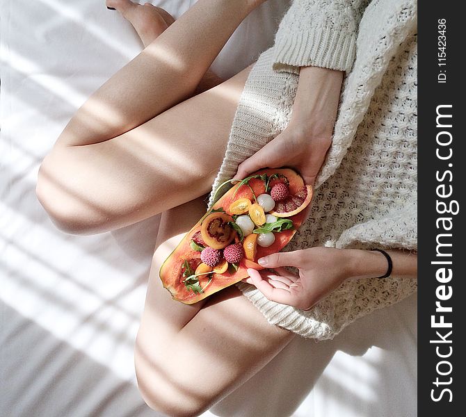 Person Holding Papaya Fruit on Bed