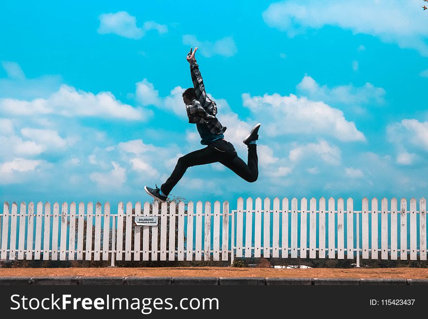 Man Jumping over White Fence