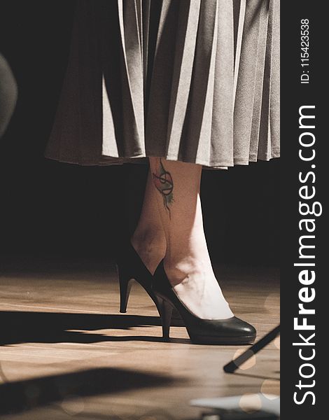 Woman in Black Heeled Shoes Standing on Brown Surface