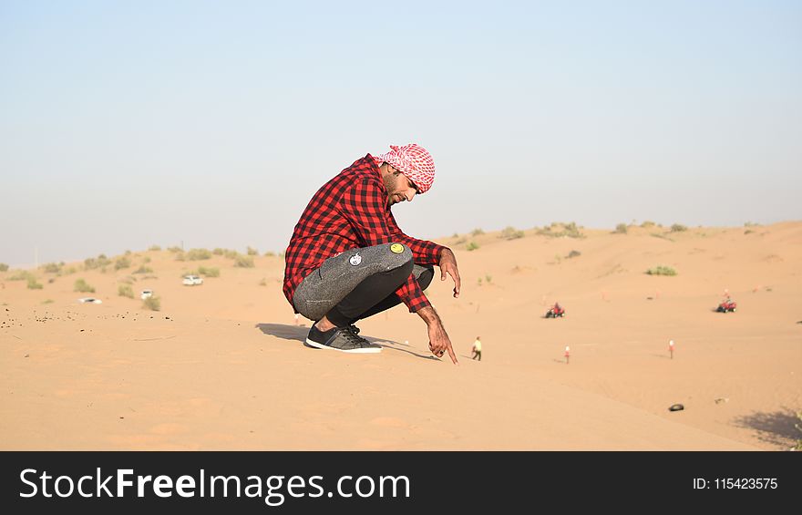 Man in Flannel Shirt Sitting on Sand
