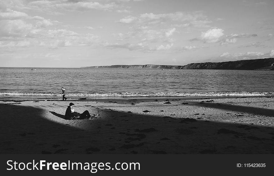 Grayscale Photo of a Man on Sand Near the Sea